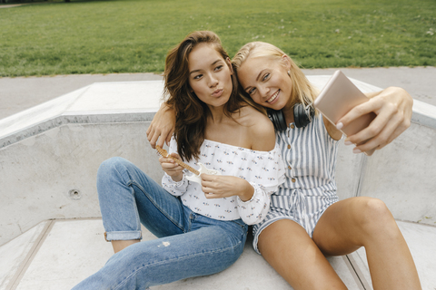 Two happy young women taking a selfie in a skatepark stock photo