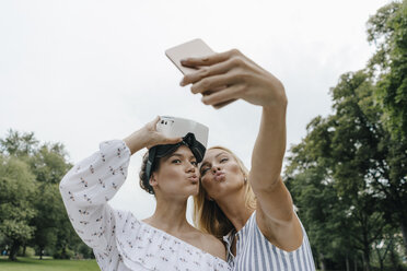 Zwei junge Frauen mit VR-Brille machen ein Selfie in einem Park - KNSF03080