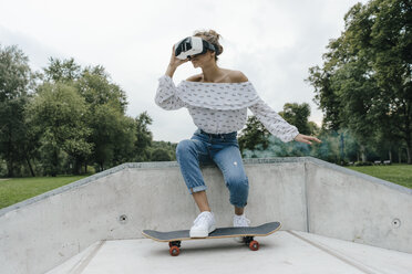 Junge Frau mit Skateboard und VR-Brille in einem Skatepark - KNSF03081