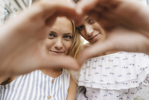 Zwei lächelnde junge Frauen, die mit ihren Händen ein Herz formen - KNSF03090