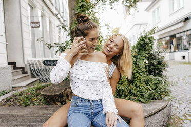 Two happy young women with cell phone in the city - KNSF03092