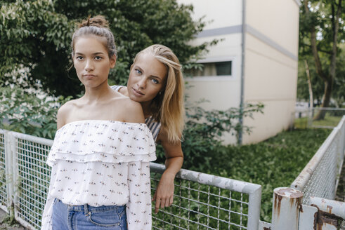 Portrait of two young women standing at a fence - KNSF03093