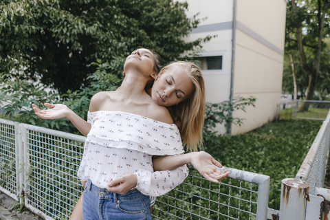 Two young women relaxing at a fence stock photo