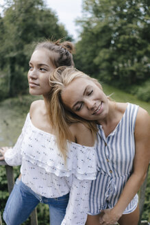 Smiling young woman resting on female friend's shoulder - KNSF03102