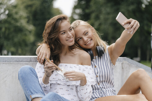 Zwei glückliche junge Frauen machen ein Selfie in einem Skatepark - KNSF03117