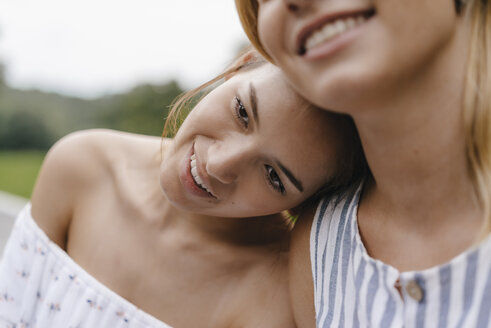 Lächelnde junge Frau, die sich an der Schulter einer Freundin ausruht - KNSF03133