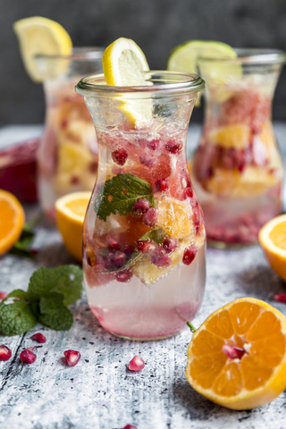 Detox-Wasser, ein Glas Wasser mit Zitrusfrüchten, Granatapfelkernen und Minze, lizenzfreies Stockfoto