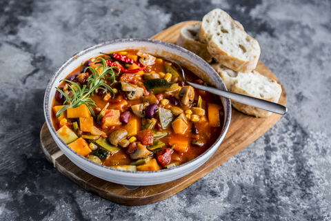 Gemüse-Chili mit Kidneybohnen, Süßkartoffeln, Champignon, Mais, Zuckerschoten, Baguette in Schale, lizenzfreies Stockfoto