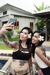 Zwei glückliche Frauen, die ein Selfie im Schwimmbad machen - IGGF00237