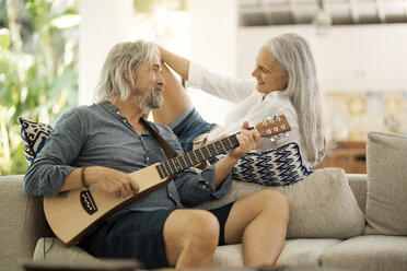 Senior man taking selfie at poolside while his wife is playing the guitar - SBOF00931