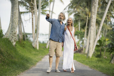 Hübsches älteres Paar schlendert durch eine tropische Landschaft mit Palmen - SBOF00958
