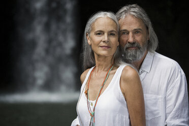 Portrait of handsome senior couple in front of tropical waterfall - SBOF00963