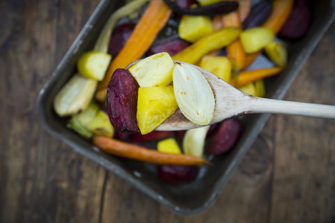 Wintergemüse aus dem Ofen, Karotten, Rote Bete, Kartoffeln und Pastinaken im Bratentopf, auf Holzlöffel, lizenzfreies Stockfoto