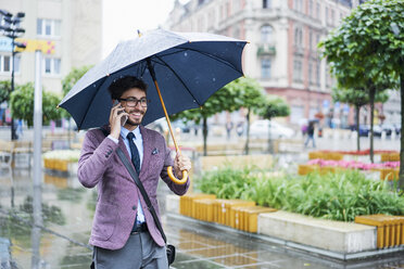 Modischer Geschäftsmann am Telefon an einem regnerischen Tag in der Stadt - BSZF00099