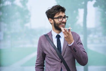 Portrait of happy young businessman on the phone outdoors - BSZF00103