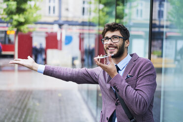 Porträt eines jungen Geschäftsmannes am Telefon an einem regnerischen Tag - BSZF00104