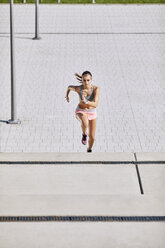 Fitte junge Frau läuft auf einer Treppe - BSZF00125