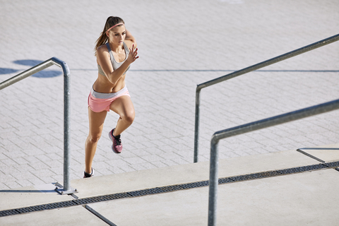 Fitte junge Frau läuft auf einer Treppe, lizenzfreies Stockfoto