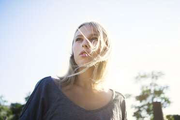 Portrait of blond young woman with blowing hair at backlight - KNSF03137