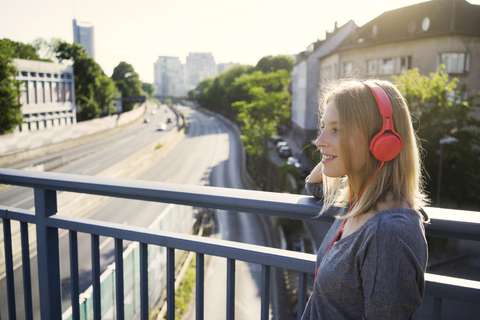 Porträt einer lächelnden jungen Frau, die mit Kopfhörern Musik hört, lizenzfreies Stockfoto