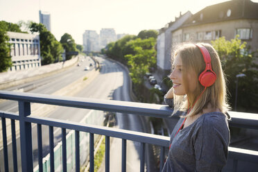 Portrait of smiling young woman listening music with headphones - KNSF03145