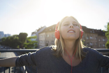 Portrait of young woman with eyes closed listening music with headphones - KNSF03147