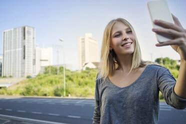 Portrait of smiling young woman taking selfie with smartphone - KNSF03153