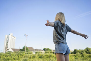 Back view of young woman with arms outstretched - KNSF03154