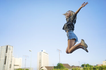 Glückliche junge Frau, die in die Luft springt - KNSF03155