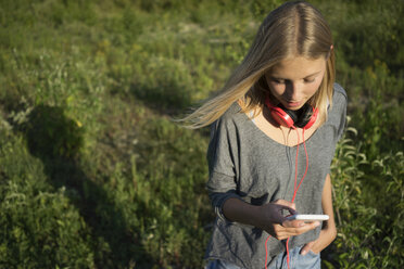 Young woman on a meadow using cell phone - KNSF03159