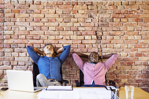 zwei Kollegen, die entspannt im Büro sitzen und eine Pause machen, lizenzfreies Stockfoto