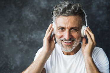 Mature man smiling, wearing headphones - HAPF02459