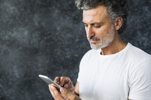 Älterer Mann, der ein Smartphone benutzt und Textnachrichten sendet, lizenzfreies Stockfoto