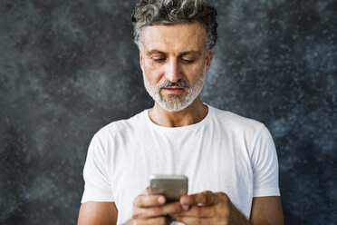 Älterer Mann, der ein Smartphone benutzt und Textnachrichten sendet - HAPF02463