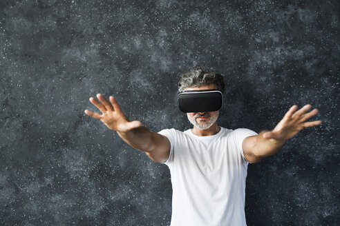 Mature man wearing VR glasses reaching out with hands - HAPF02466