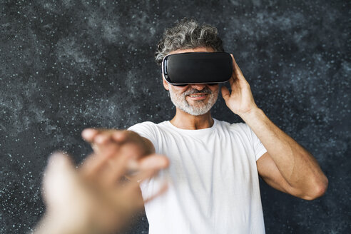 Mature man wearing VR glasses reaching out with hands - HAPF02467