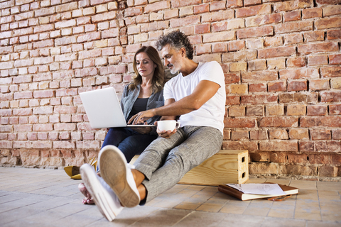 Geschäftsmann und Frau sitzen in einem Loft, benutzen einen Laptop und gründen ein Start-up-Unternehmen, lizenzfreies Stockfoto