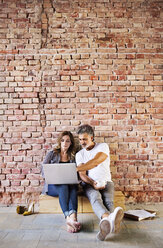 Geschäftsmann und Frau sitzen in einem Loft, benutzen einen Laptop und gründen ein Start-up-Unternehmen - HAPF02478