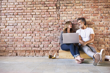 Geschäftsmann und Frau sitzen in einem Loft, benutzen einen Laptop und gründen ein Start-up-Unternehmen - HAPF02479