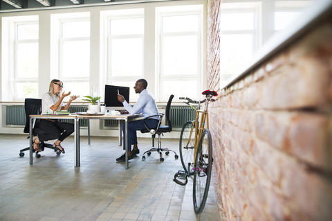 Kollegen in einem Start-up-Unternehmen, die im Büro sitzen und diskutieren, lizenzfreies Stockfoto
