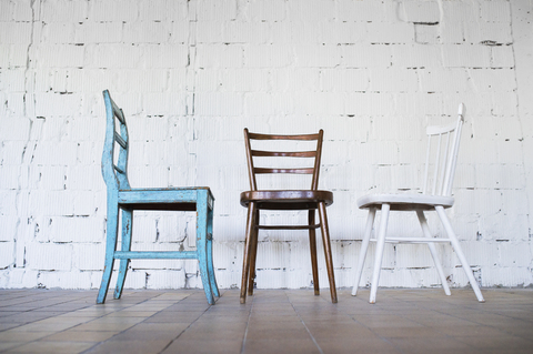 Leere Stühle vor weißer Backsteinwand, lizenzfreies Stockfoto