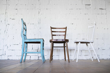 Empty chairs against white brick wall - HAPF02503