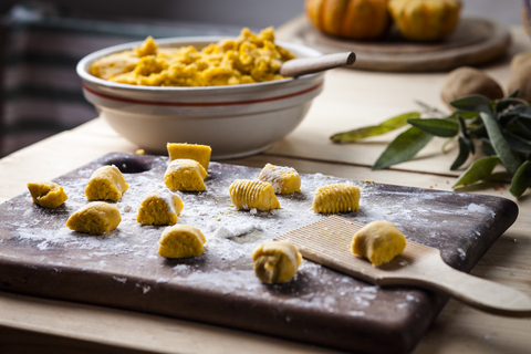 Vorbereitung der Kürbisgnocchi, Ausrollen auf einem Holzbrett, lizenzfreies Stockfoto