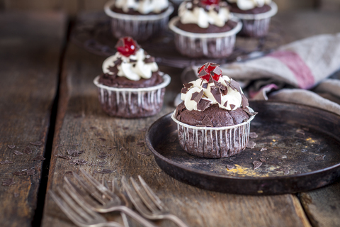 Schwarzwälder-Kirsch-Muffins mit Sahnetopping und Kirsche, lizenzfreies Stockfoto