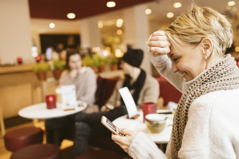 Junge glückliche Frau benutzt Smartphone in einem Café, lizenzfreies Stockfoto