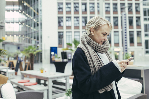 Blonde Frau benutzt ein Mobiltelefon, lizenzfreies Stockfoto