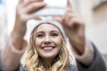 Portrait of laughing young woman taking selfie with smartphone - FMKF04662