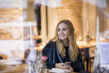 Portrait of smiling young woman waiting in a restaurant - FMKF04673
