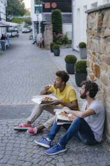 Zwei Freunde essen Pizza zum Mitnehmen in der Stadt - KNSF03169