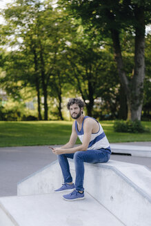 Mann mit Mobiltelefon im Skatepark sitzend - KNSF03176